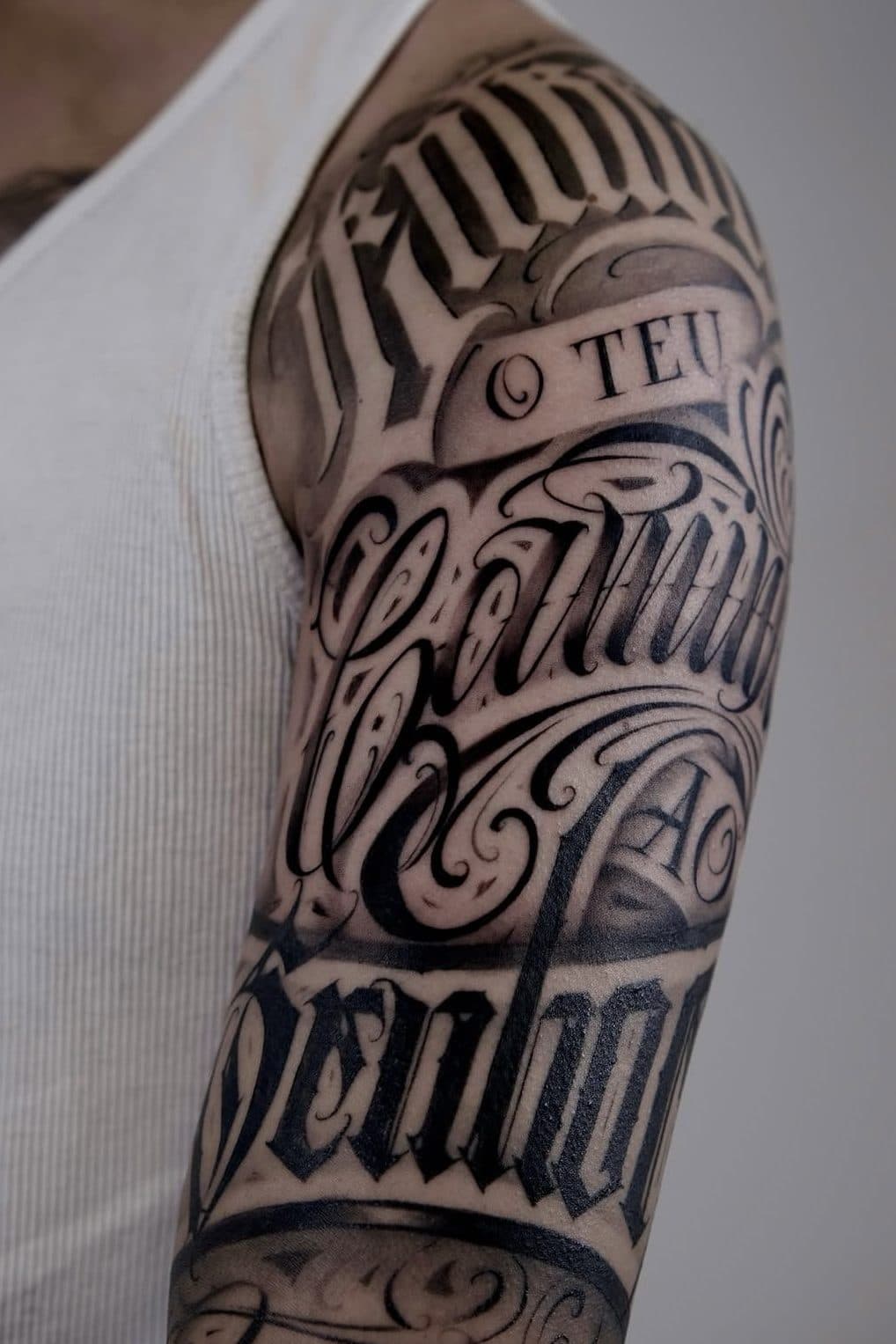 Lettering no ombro e braço com a frase «O teu caminho ao Senhor» em blackletter e script