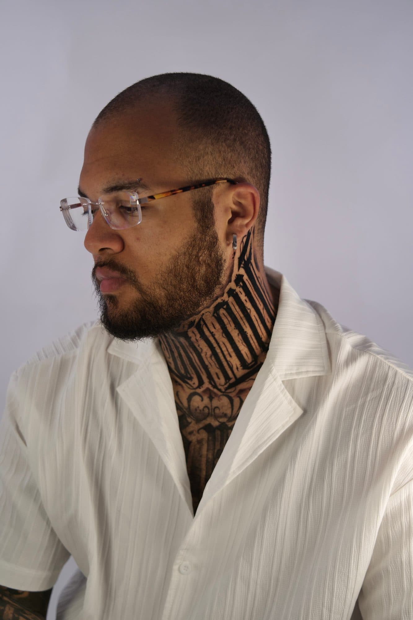 Lettering em blackletter no pescoço de um homem de óculos e camisa branca