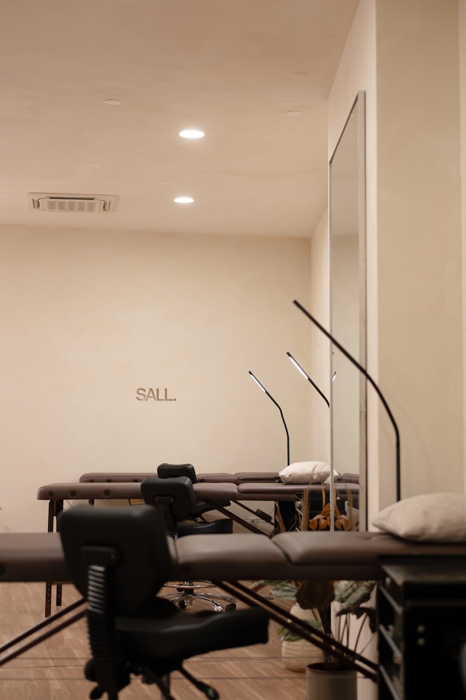 Sala de tatuagem do Sall Porto, com macas, cadeiras pretas, candeeiros de braço e o nome SALL na parede creme